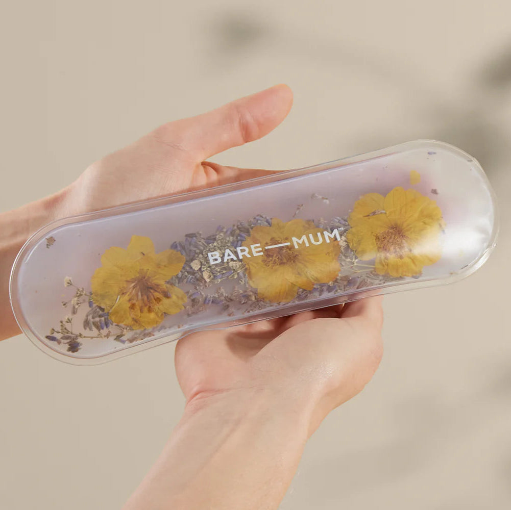 Hand holding a transparent case with yellow flowers and 'BARE MUM' text against a blurred background