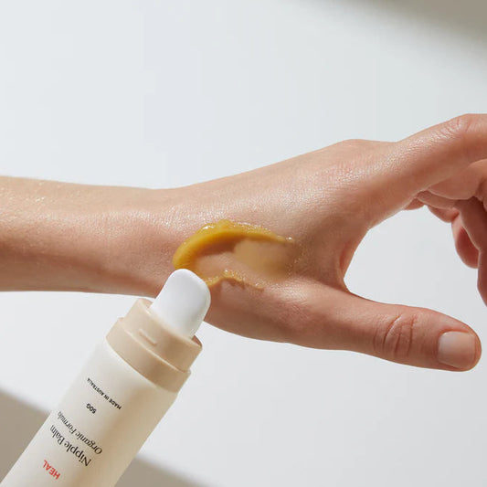 Hand applying a nipple balm on dry skin Bare Mum Nipple Balm bottle