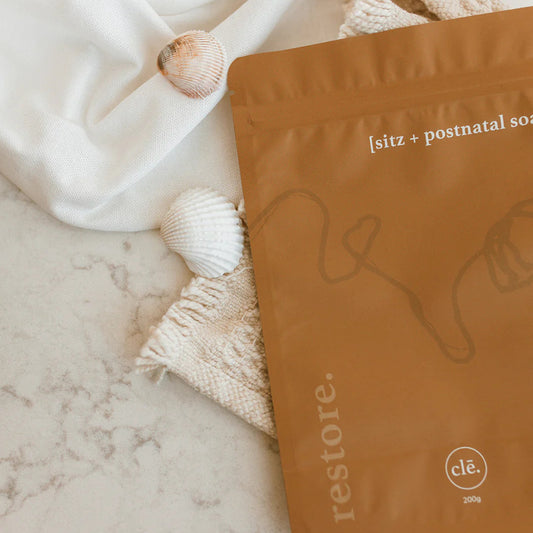 Brown package labeled 'restore' on a marble surface with white towels and shells.