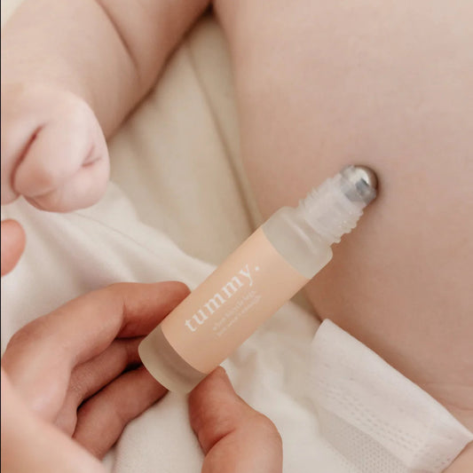 Person applying Cle Tummy Essentials Oil Roller to a baby's stomach area.