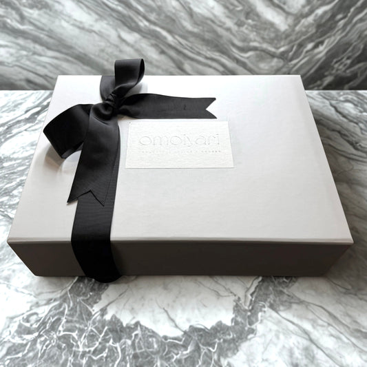 White Omoiyari gift box with a black ribbon on a marble surface