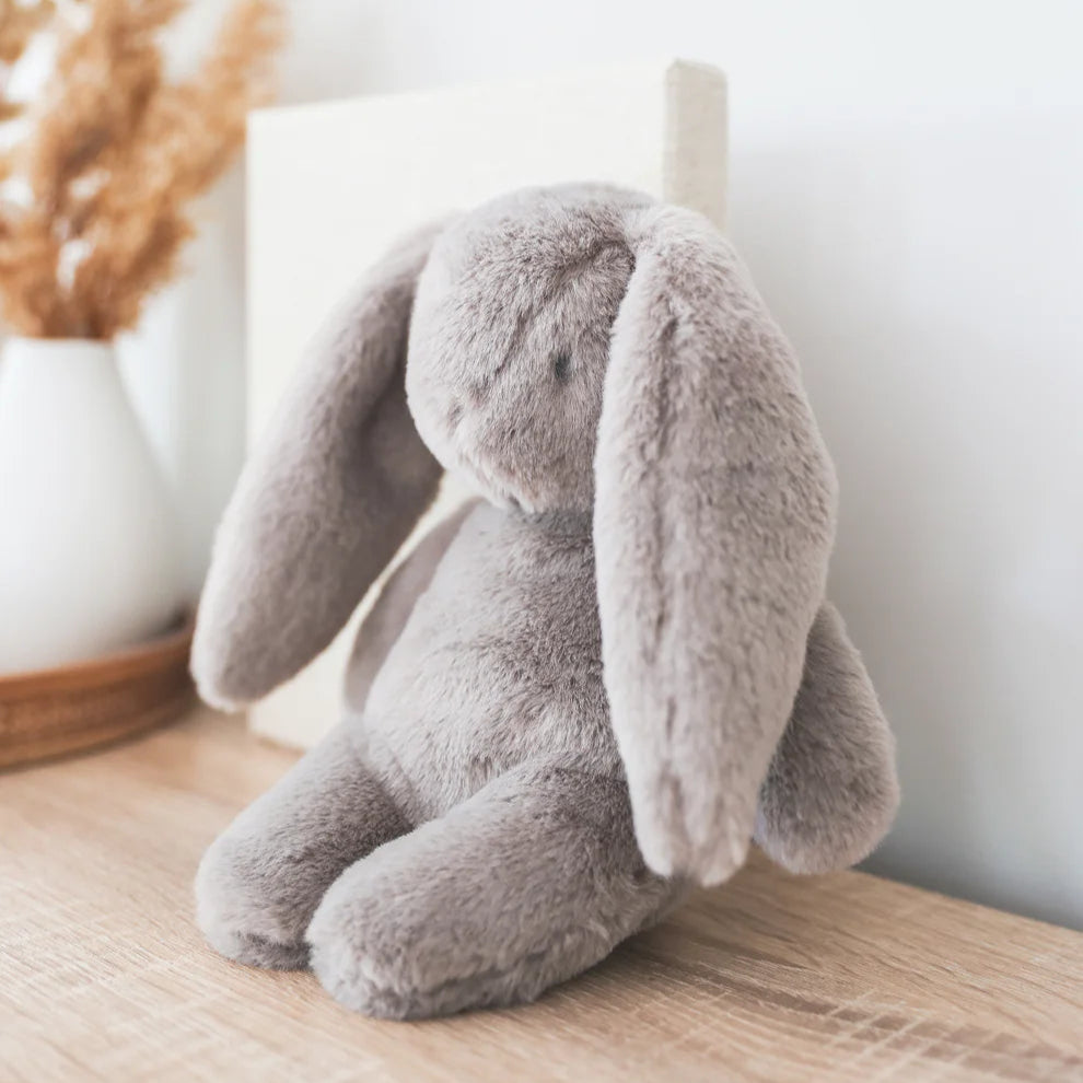 Plush bunny toy on a wooden surface with a blurred background