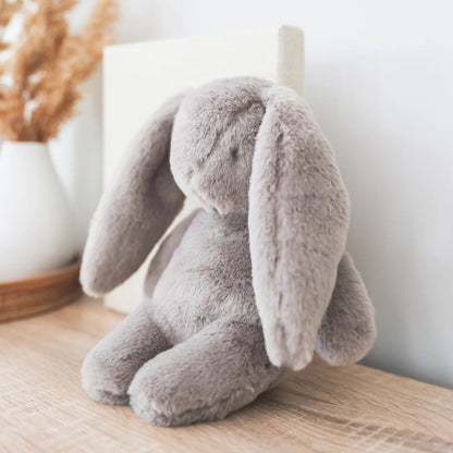 Plush bunny toy on a wooden surface with a blurred background