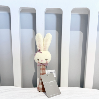 Plush toy with a Alimrose card on a bed with Cot headboard