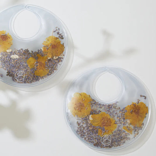 Two clear breast pad inserts with dried flowers on a light background