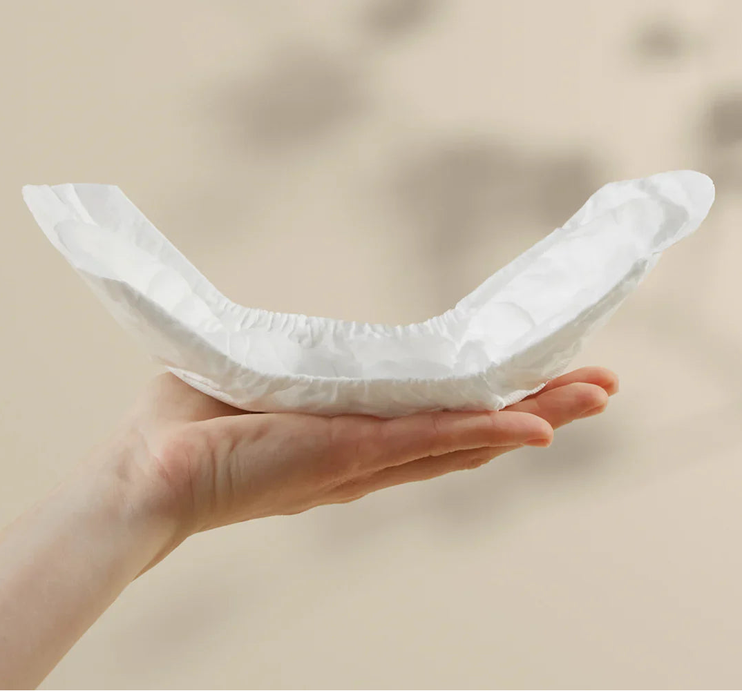 Bare Mum herbal infused postpartum sitting on top of a woman's hand to show the curvature design to fit comfortably.