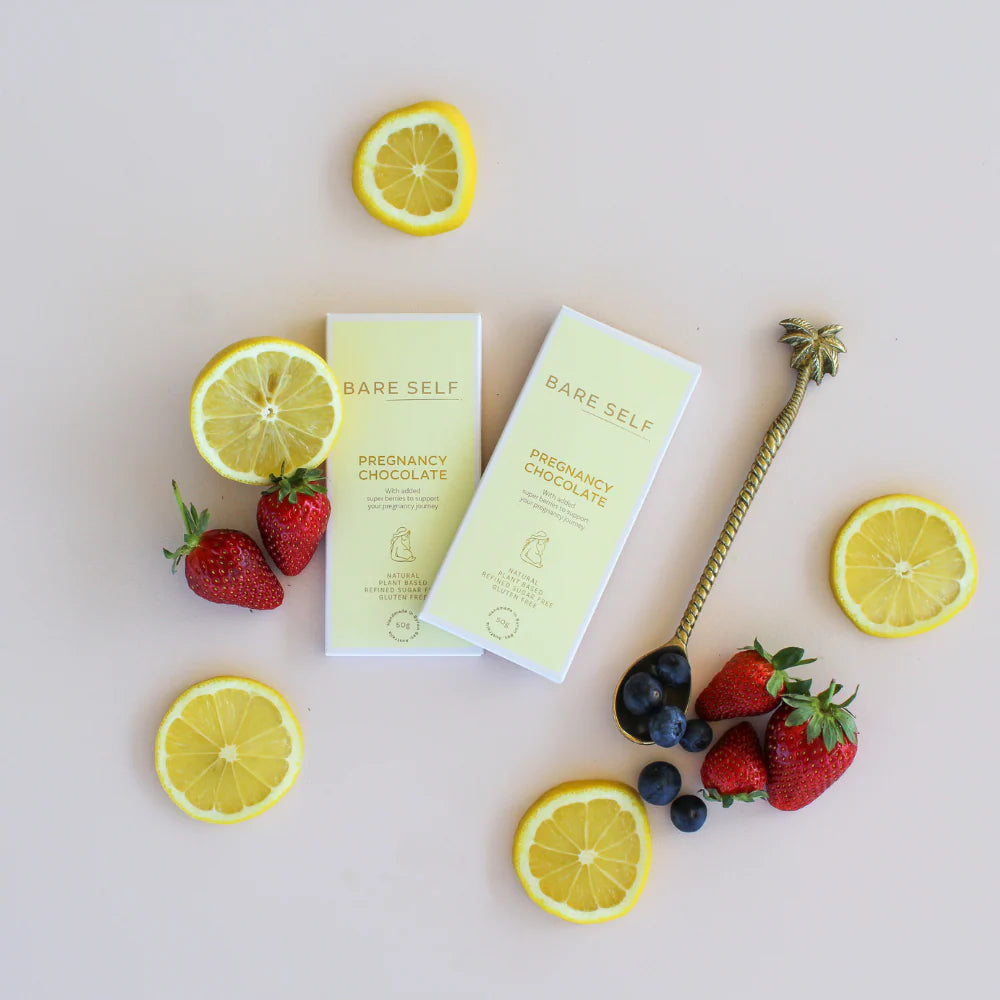 Bare Self pregnancy chocolate boxes with lemons, strawberries, and blueberries on a light background