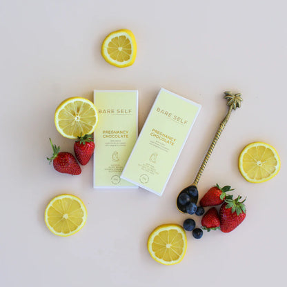 Bare Self pregnancy chocolate boxes with lemons, strawberries, and blueberries on a light background