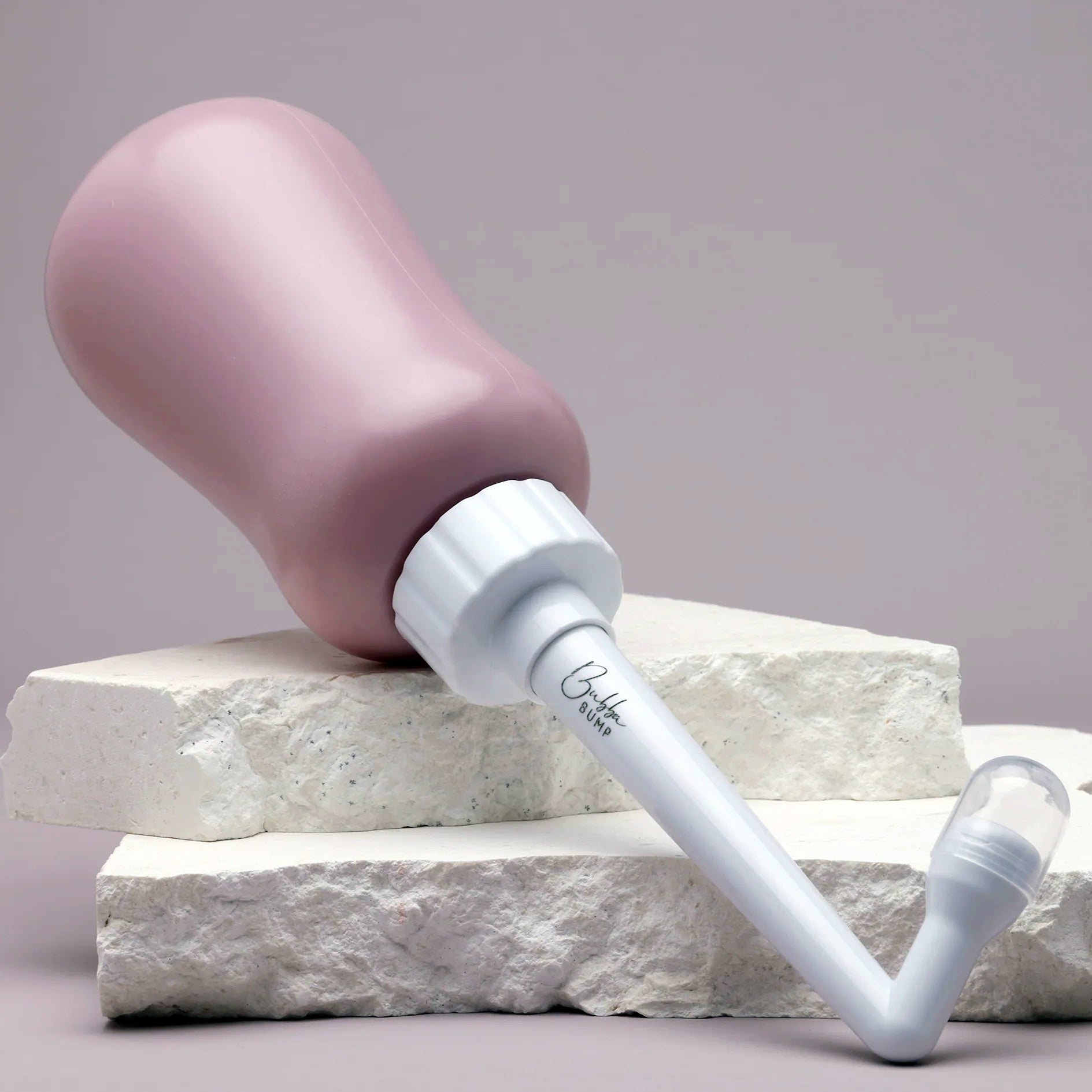 Pink and white peri bottle with pump on a light grey background