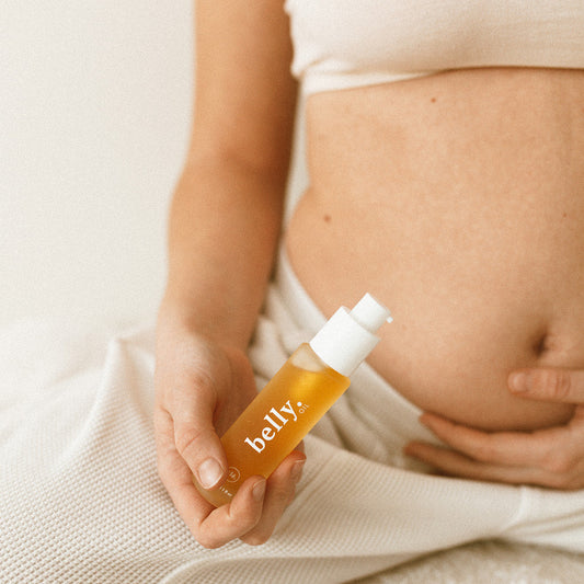 Pregnant person holding a bottle labeled 'belly' against their stomach.