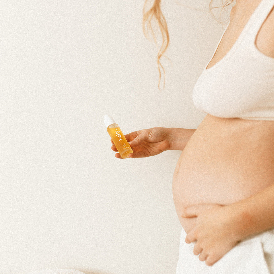 Pregnant woman applying belly oil to her stomach