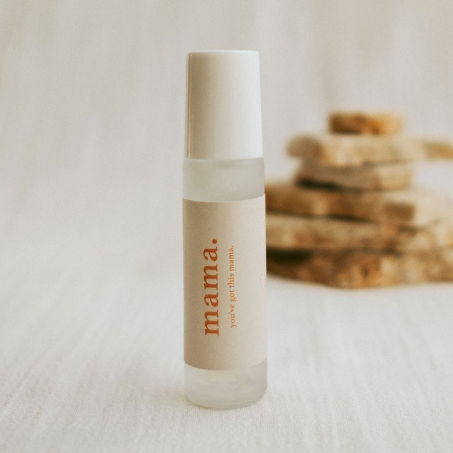 Skincare bottle labeled 'mama.' on a textured surface with blurred background
