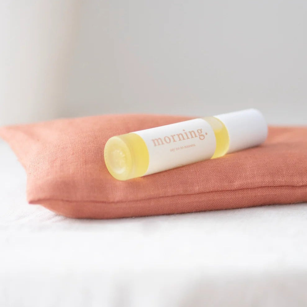Morning essentials oil roller on a pink pillow with a white background