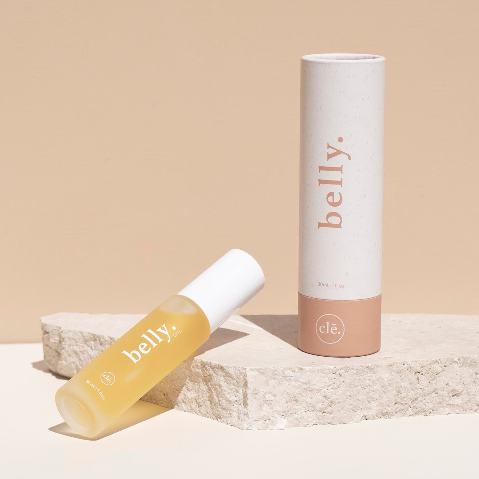 Belly skincare product with applicator and tube on a beige background