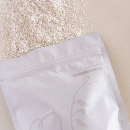 Open white packaging bag with a floral design on a beige background, containing a white oat substance.