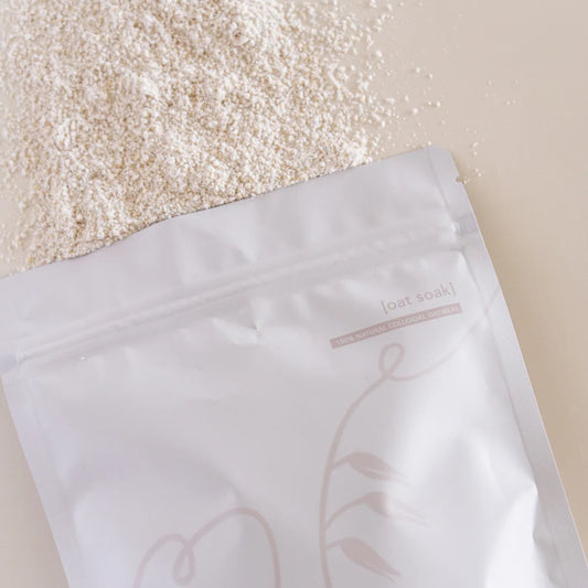 Open white packaging bag with a floral design on a beige background, containing a white oat substance.