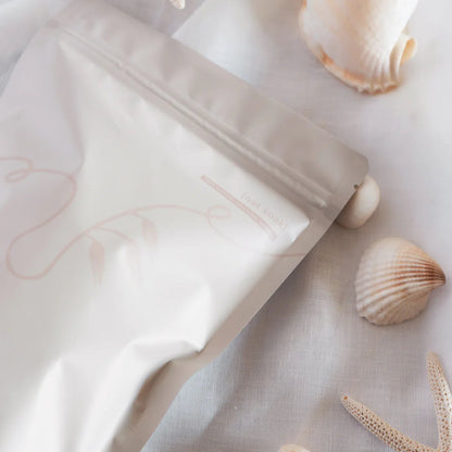 White skincare product with seashells and starfish on a light background