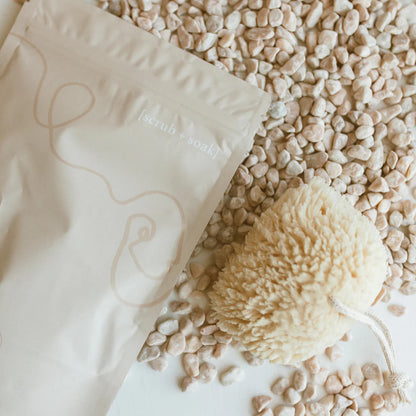 White sponge bar with a decorative design on a white surface with small stones and pebbles.