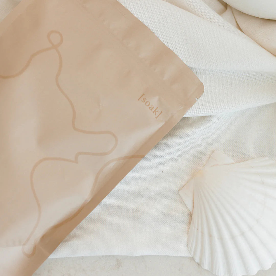 Relax Bath Soak bag on a marble surface with a shell and white object in the background