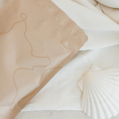 Relax Bath Soak bag on a marble surface with a shell and white object in the background