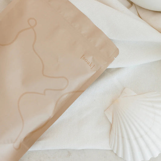 Relax Bath Soak bag on a marble surface with a shell and white object in the background