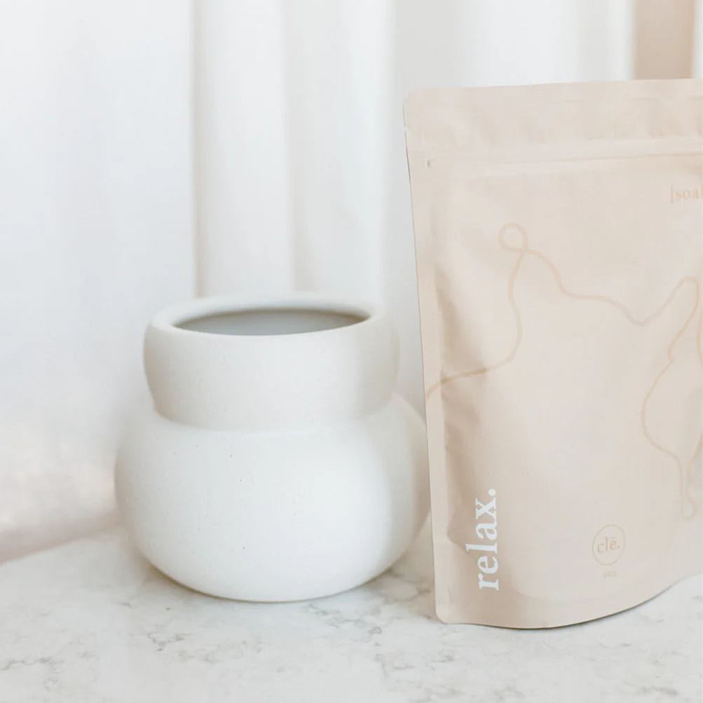 White mug and beige cushion with 'relax' text on a marble surface