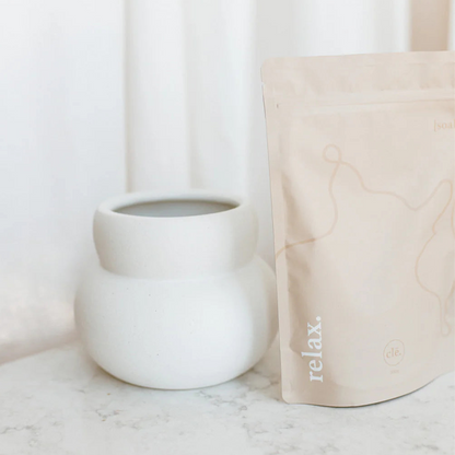 White mug and beige cushion with 'relax' text on a marble surface