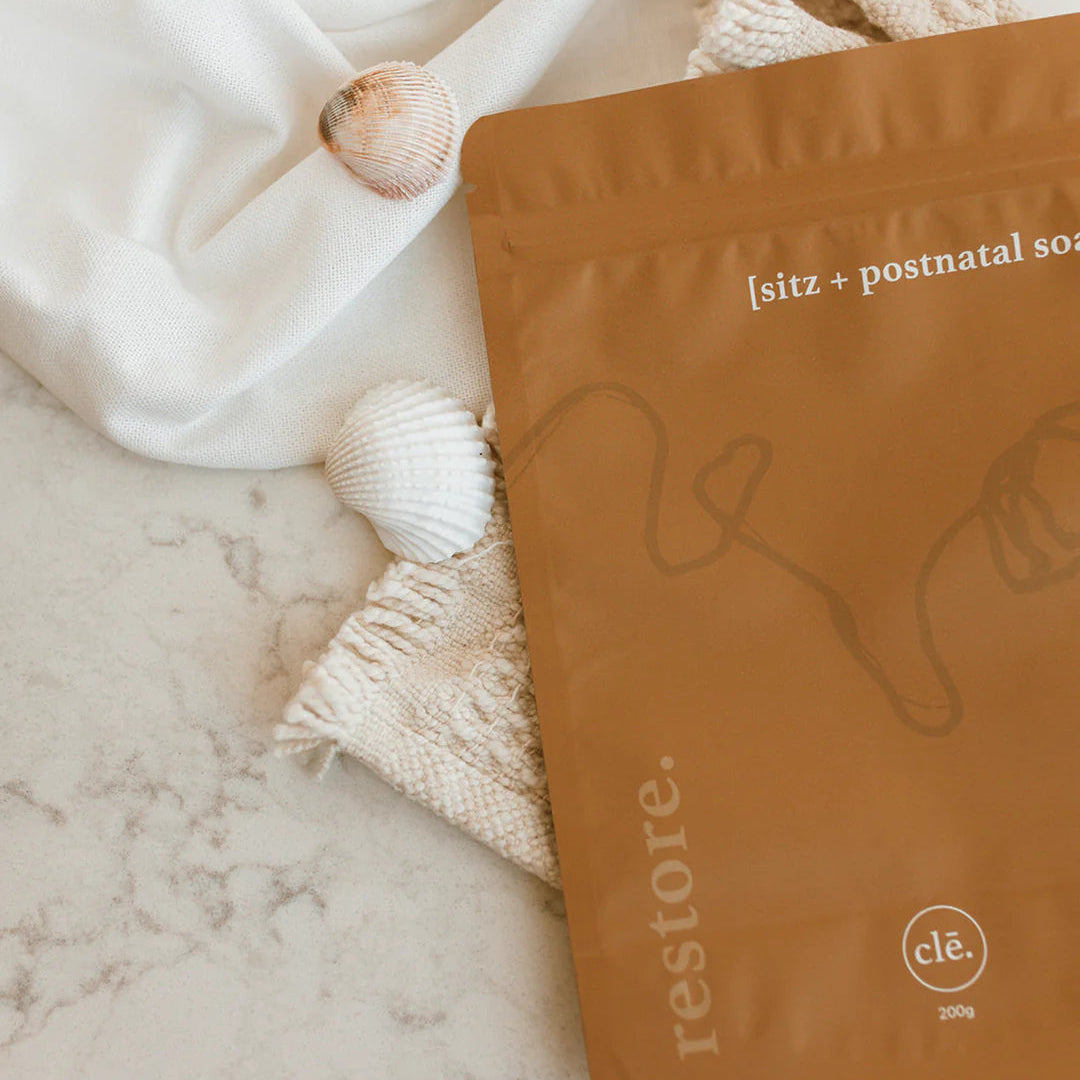 Brown package labeled 'restore' on a marble surface with white towels and shells.