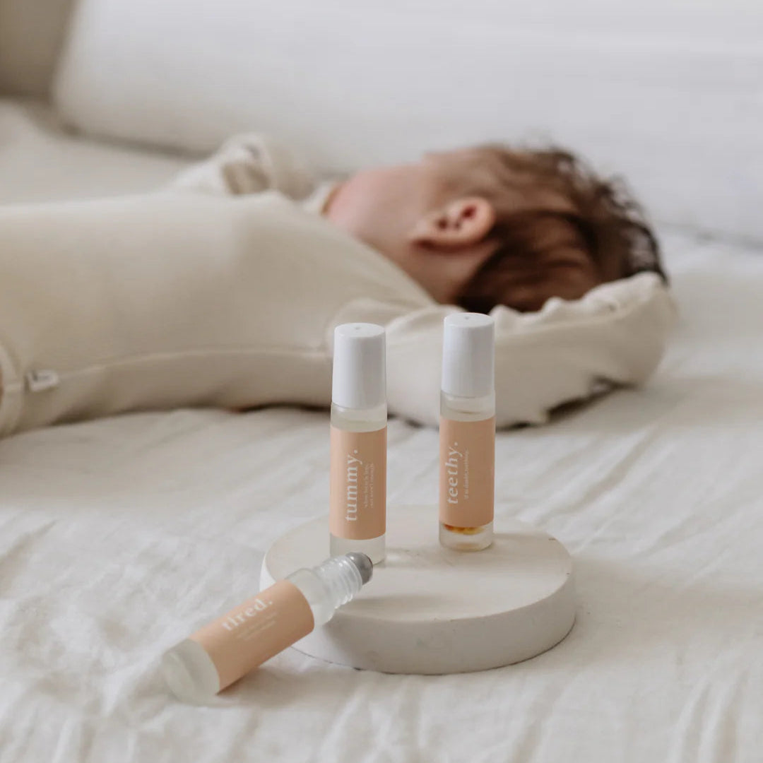 Baby lying on a bed with skincare products in the foreground