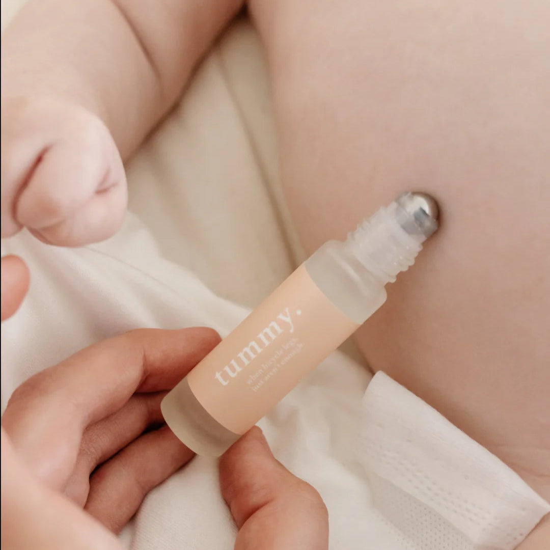 Person applying Cle Tummy Essentials Oil Roller to a baby's stomach area.