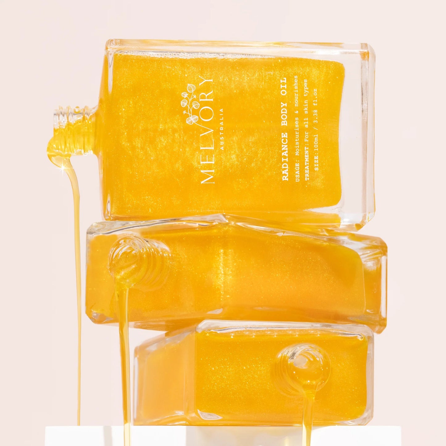 Three Radiance Oil bottles on a light pink background, featuring the brand 'Melvory'.
