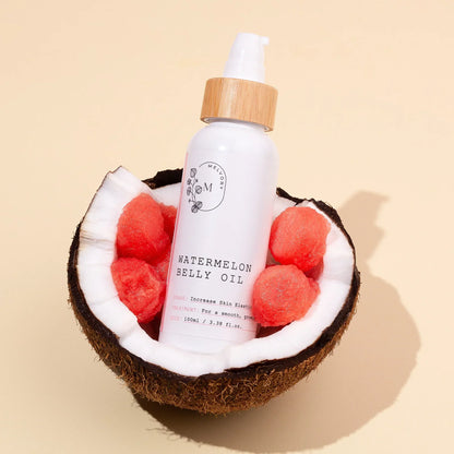 Bottle of watermelon belly oil in a coconut with watermelon pieces on a beige background