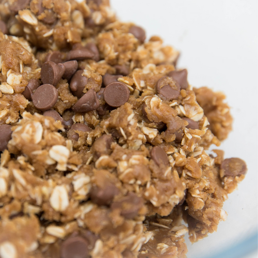 Close-up of a bowl filled with oatmeal cookie dough with chocolate chips.