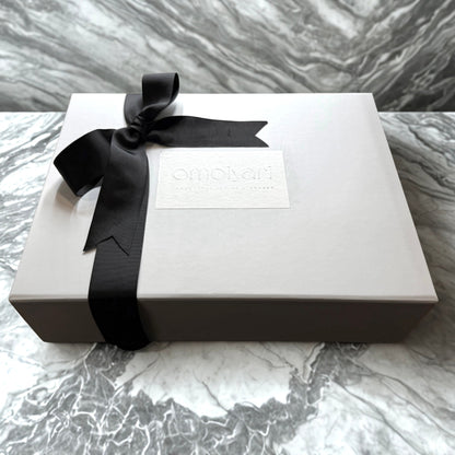 White Omoiyari gift box with a black ribbon on a marble surface