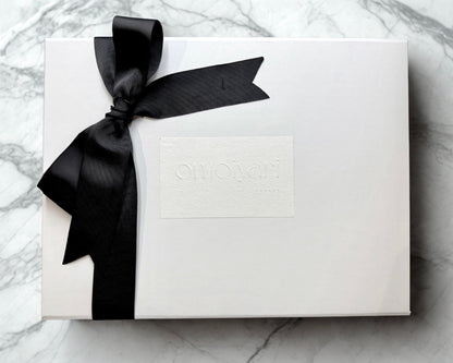 White Omoiyari gift box with a black ribbon on a marble surface