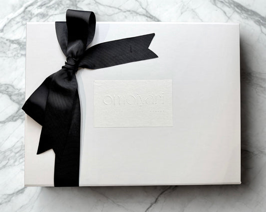 White Omoiyari gift box with a black ribbon on a marble surface