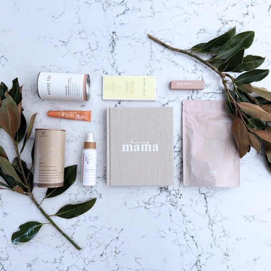 Omoiyari Glow & Grow Luxe gift hamper box - Skincare products, organic cacao and tea, mama pregnancy journal, pregnancy chocolate, stretch mark oil, lip balm and green magnolia leaves on a marble surface