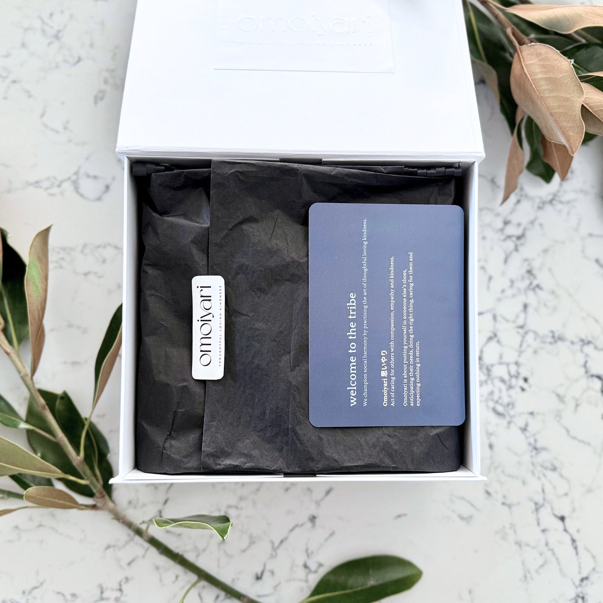 Omoiyari gift hamper box - magnetic lid is open and there is black tissue paper with an Omoiyari label and card