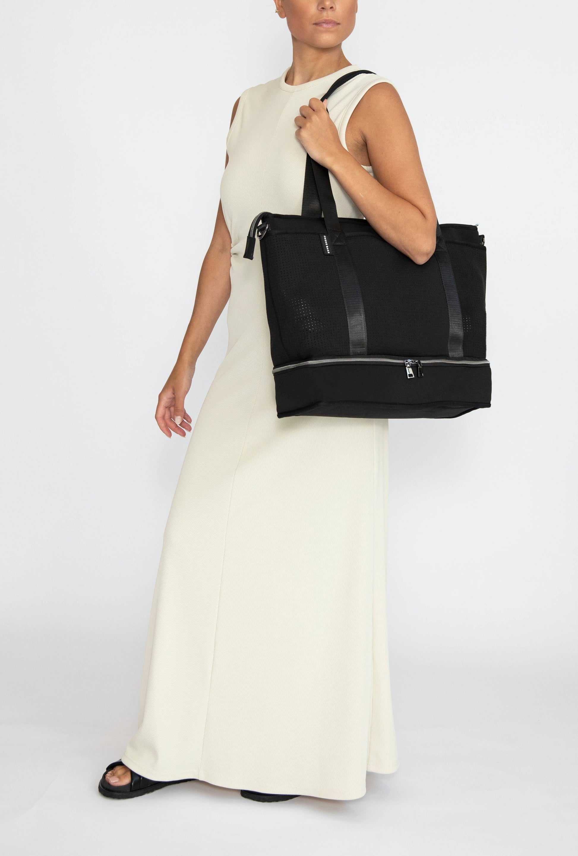 Woman in white dress holding Prene The Saturday Bag