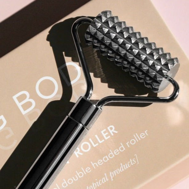 Double-headed roller tool with pyramid-shaped head on a pink background