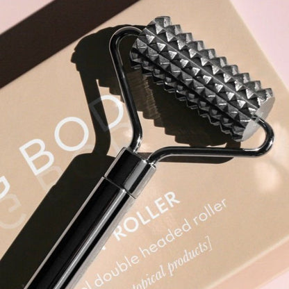 Double-headed roller tool with pyramid-shaped head on a pink background