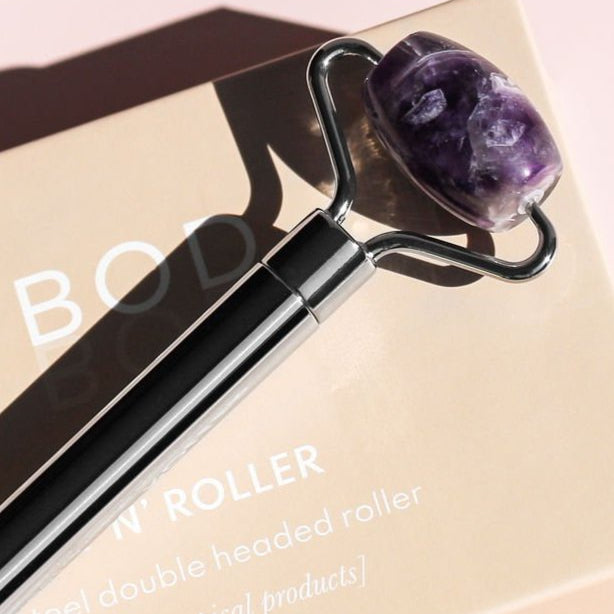 Glowing roller with purple stone head on a pink background
